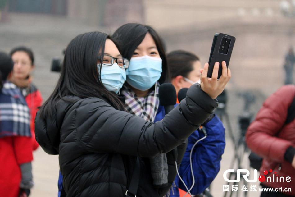  3月3日，全國政協十二屆二次會議在北京開幕，當日北京再次出現霧霾天氣。圖為眾多記者在天安門廣場戴著口罩採訪前來參加政協會議的全國政協委員。攝影：姚毅婧