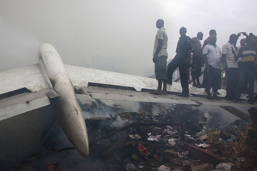 2012年6月3日，尼日利亚丹纳航空公司一架客机在拉各斯机场附近坠毁，并撞上一座两层建筑物，造成190余人死亡。这是当地居民站在坠机现场的飞机残骸上（2012年6月3日摄）。新华社/美联 