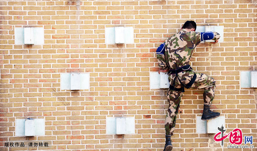 借助墙上的凸起，一名武警特战队员在进行特种攀登科目练兵。中国网图片库 李科/摄