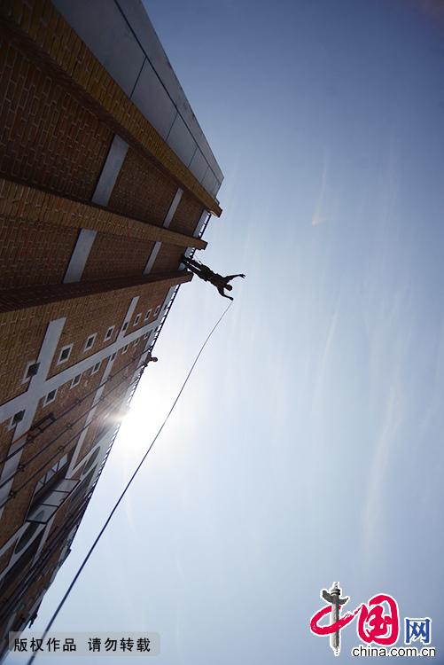 在高处，武警特战队员一跃而下，进行高空锁降科目的练习。中国网图片库 李科/摄