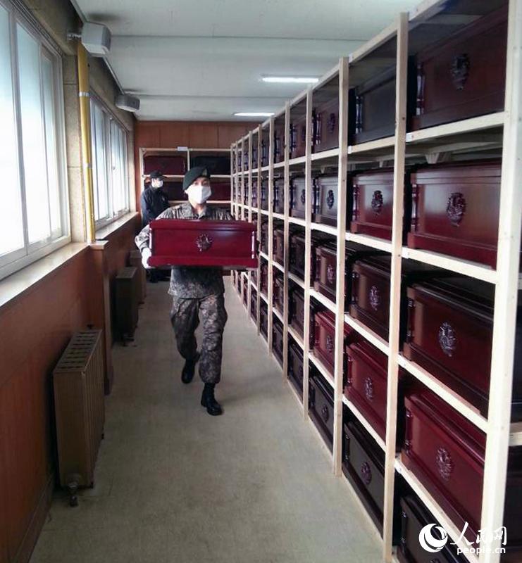 韩方起运仪式开始前，韩军人将装有志愿军遗骸的棺木搬运上车。（人民网 张悦摄）