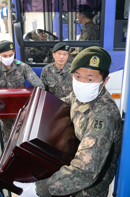 圖為南韓軍人往車上運送棺木。（人民網 張悅攝）
