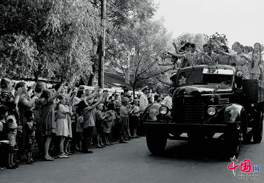 1956年,长春第一汽车制造厂试制出第一批解放牌载重汽车，帮助该厂建设的苏联专家的亲属们与当地人民一起，为这一重大成就而欢呼。