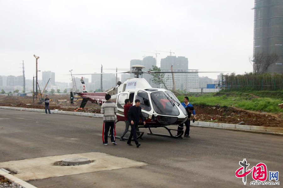 2013年4月20日，江西省九江市某樓盤附近，一架B—7792型直升機不停起降，搭載購房者從空中觀賞九江市區美景。圖為從空中觀光回來的購房者走出直升機。 中國網圖片庫 魏東升攝影