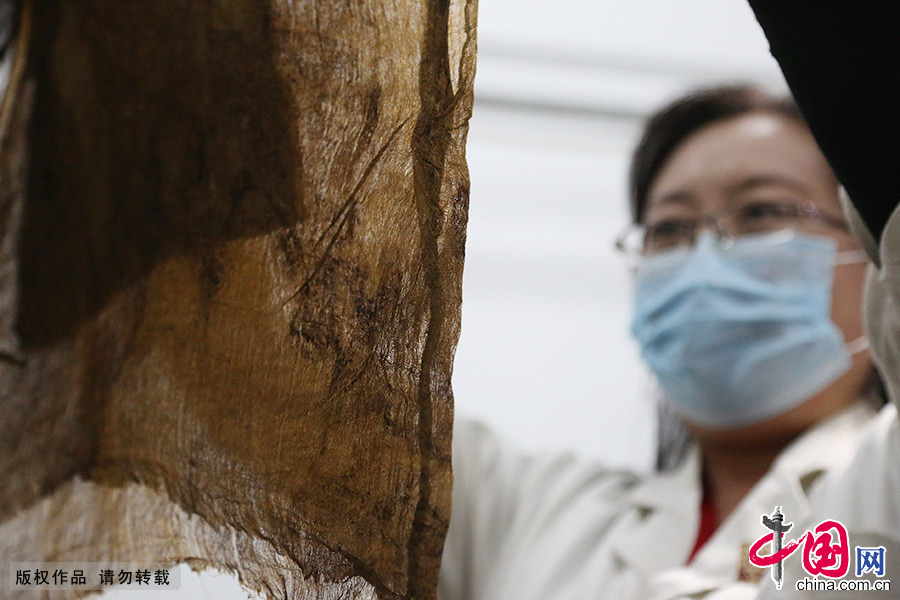 在契丹女尸库房，藏品管理员包龙梅对修复好的丝帛文物进行登记。