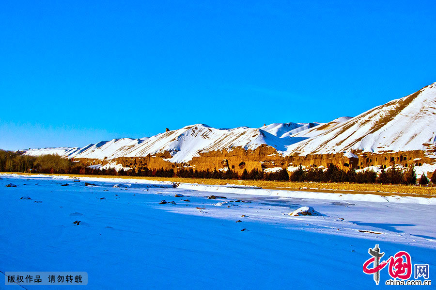 图为雪后的敦煌，摄于莫高窟北区。在2012年第一场雪后的清晨，崖体的颜色和雪的颜色相映成趣，十分美丽。 中国网图片库 徐海洋 摄