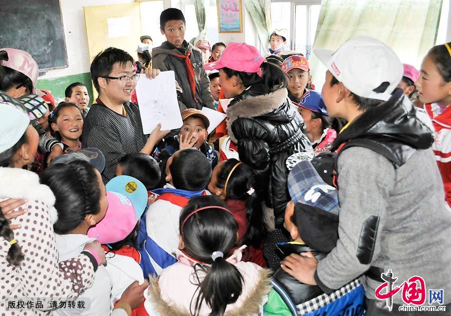图为支教团队成员在教藏族学生画画，面对镜头，孩子们难掩好奇心。