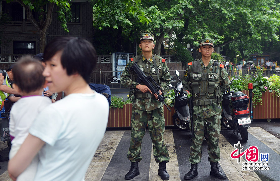 2014年05月25日，浙江省杭州市，游客从在杭州西湖断桥处执勤的武警前走过。
