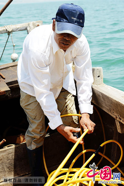 船上的陈瑞录在拉收海参捕捞师氧气管。这条氧气管为海参捕捞师提供生命保障。
