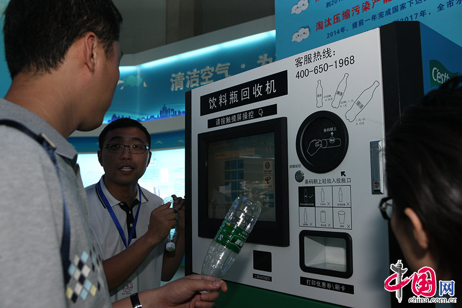 6月9日，在北京节能环保展的政府展区内，观众人员向观众现场展示饮料瓶回收机使用方法。中国网记者 董宁摄影