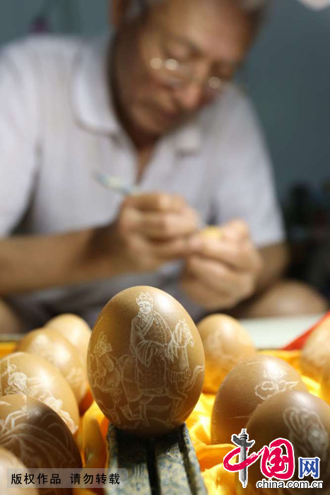 虎占林在鸡蛋上精心创作蛋雕作品。
