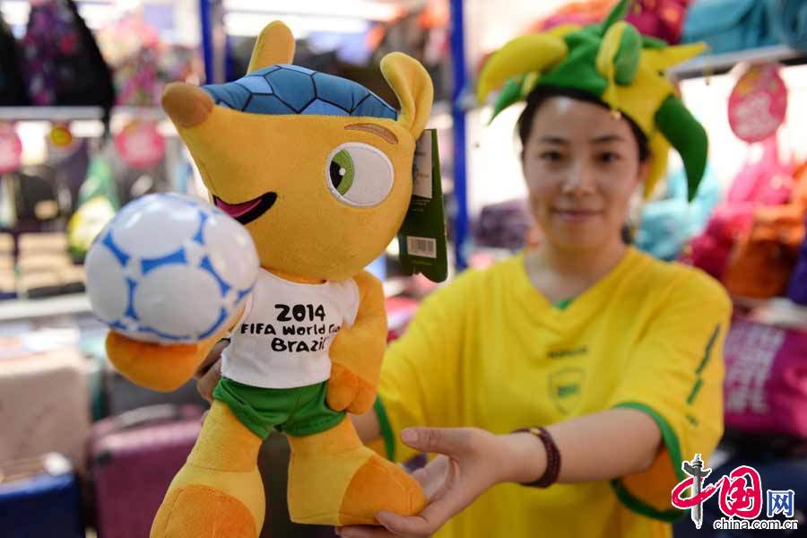 6月12日，一名店員在展示2014巴西世界盃的吉祥物福來哥。 中國網圖片庫 賴鑫琳攝影