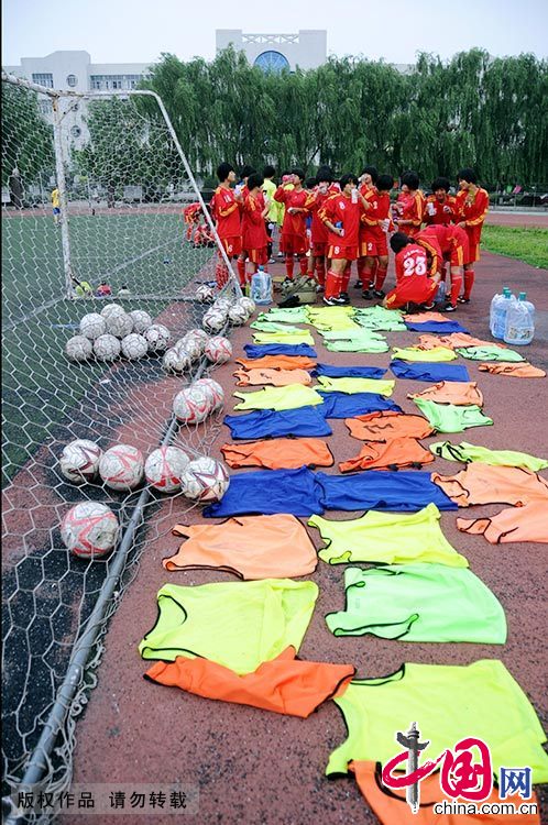 烈日炎炎，一場對抗賽結束後，“足球丫頭”們將濕透的球衣放在球場邊晾曬。