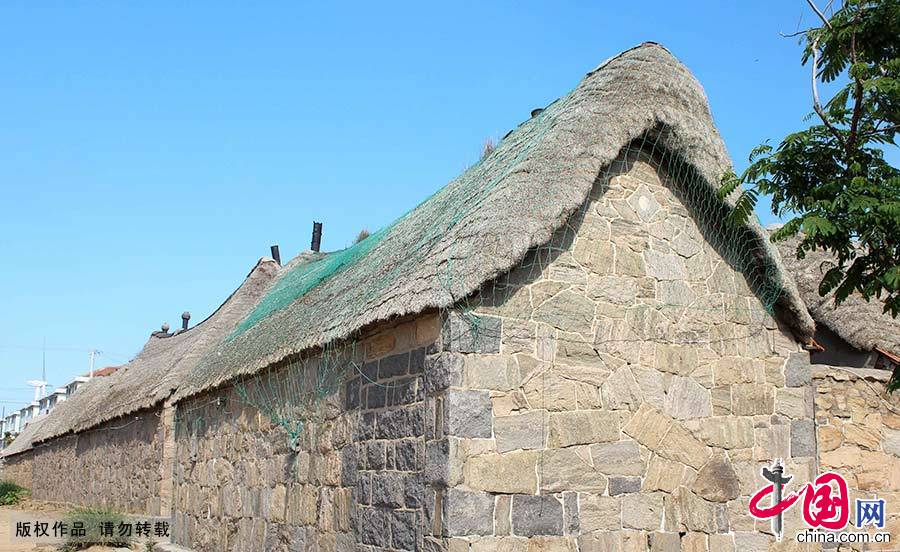 在原始石块或砖石块混合垒起的屋墙上，有着高高隆起的屋脊，屋脊上面是质感蓬松、绷着渔网的奇妙屋顶。