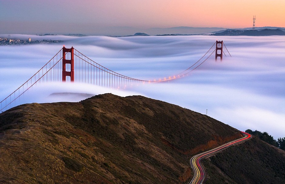 云雾缭绕下的金门大桥浪漫多情，一旁的山路蜿蜿蜒蜒，远处的旧金山却如同海市蜃楼。