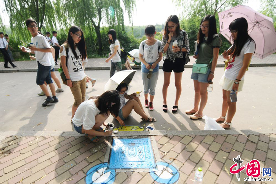 2014年6月24日，很多路過的學生駐足觀看井蓋塗鴉作品。 中國網圖片庫 王海濱攝影