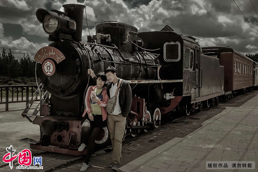 在停運多年的阿爾山窄軌蒸汽小火車頭拍照的情侶。