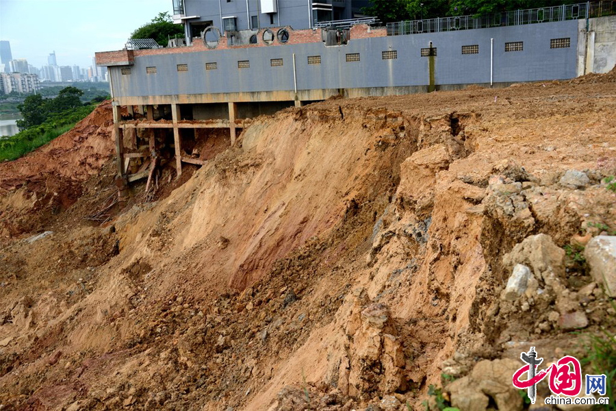 2014年7月13日，广西南宁市，柳沙半岛发生滑坡事故，泥土滑动百余米冲入邕江，小区住户一觉醒来发现住宅楼下赫现“天坑”，一幢楼的基脚祼露了出来。图片来源：CFP