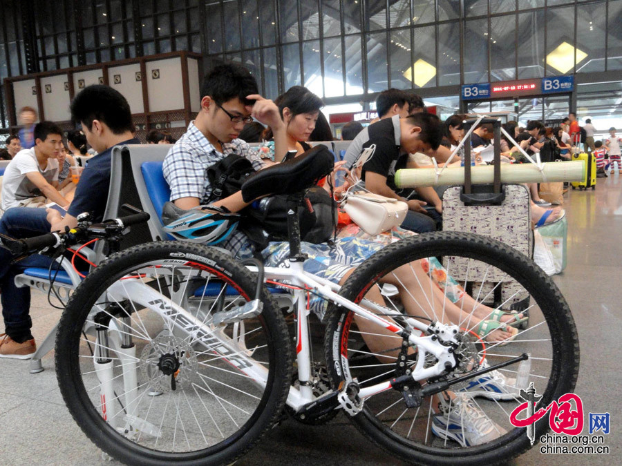 一名旅客攜帶自行車在蘇州火車站候車大廳內等候乘車。