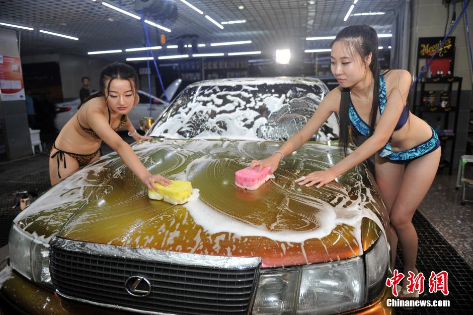 7月27日，山西太原一洗車會所內，兩名比基尼模特擔當洗車工清洗汽車，引眾人圍觀