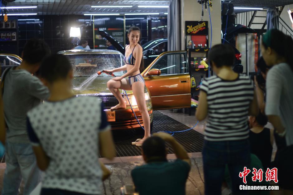 7月27日，山西太原一洗車會所內，兩名比基尼模特擔當洗車工清洗汽車，引眾人圍觀