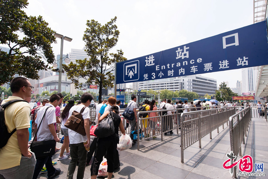  2014年7月29日中午，铁路上海站站前广场上人来人往，十分繁忙。人工售票大厅售票窗口前排起了长队，自助售票处和展厅进口处人流相当密集。图片来源：cfp