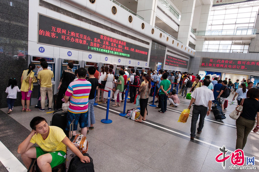  2014年7月29日中午，铁路上海站站前广场上人来人往，十分繁忙。人工售票大厅售票窗口前排起了长队，自助售票处和展厅进口处人流相当密集。图片来源：cfp