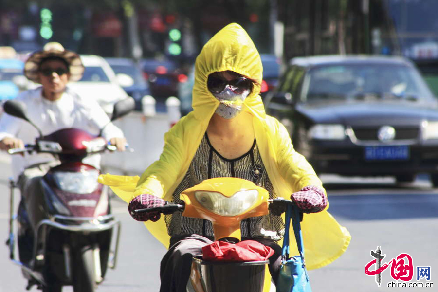  2014年7月30日上午，許多市民穿戴厚厚的衣服、帽子、眼鏡全副武裝地騎行在高溫的浙江紹興市區街頭。中國網圖片庫 李瑞昌攝影