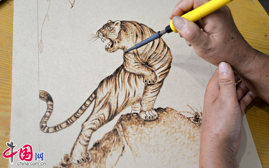 7月30日，民间艺人张振芳正在用电烙铁画出一只栩栩如生的老虎。