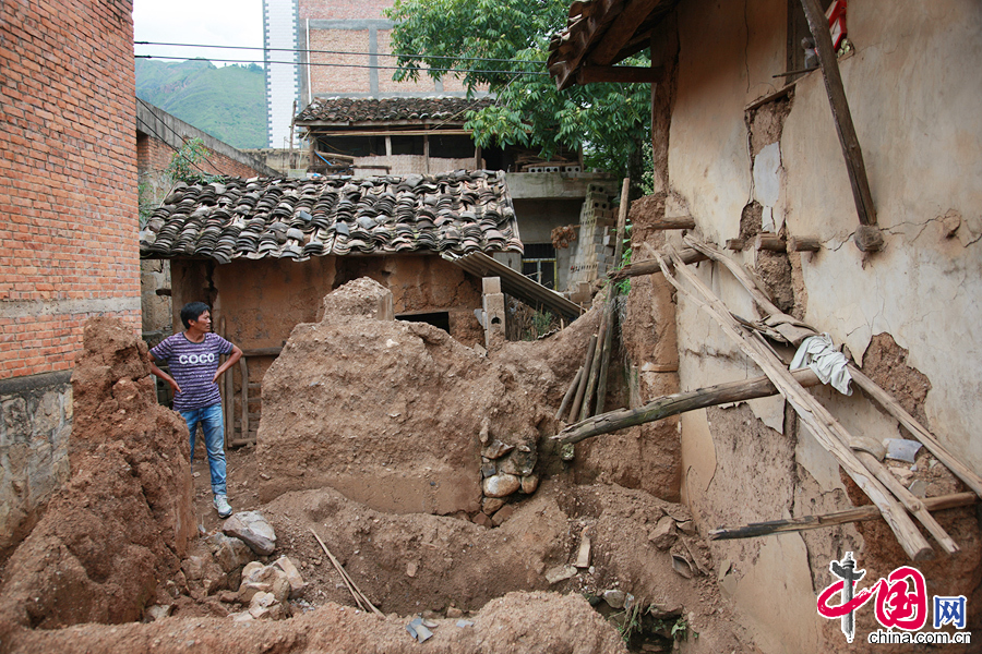 鲁甸县龙头山镇营盘村村民许宝进望着自己在地震中受损的房子，地震发生时他在帮同村村民家中办理丧事而“躲过一劫”。 中国网记者 杨佳摄影