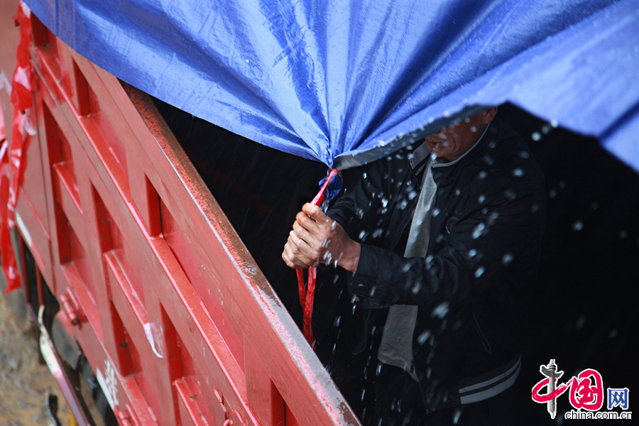 2014年8月11日，云南鲁甸火德红镇救援点，为了防止救援物资受潮，工作人员给货车盖上雨布，雨水顺着雨布倾泻而下。