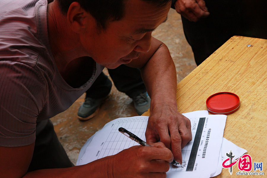 2014年8月11日，云南鲁甸南筐村，村民们领取救援物资，需要在领取单上签字按手印。