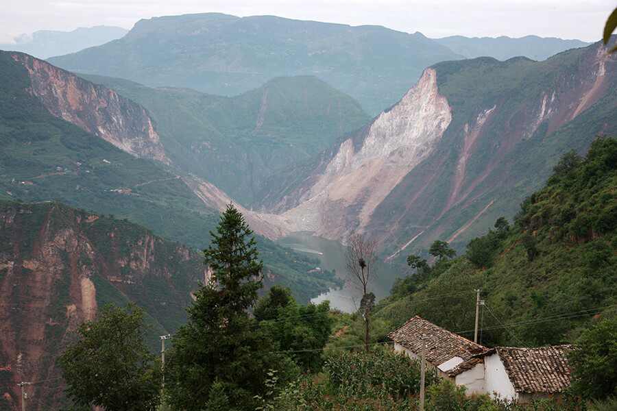 牛欄江邊的兩座山體崩塌，封住了河水，連日的暴雨讓水位快速上漲，淹沒了附近的村子。