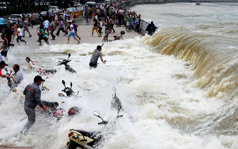 2014年8月15日，杭州，錢江潮水在杭州九溪江堤掀起巨浪，瞬間打濕了觀潮者，一位淡定哥手持手機在潮水中拍攝。