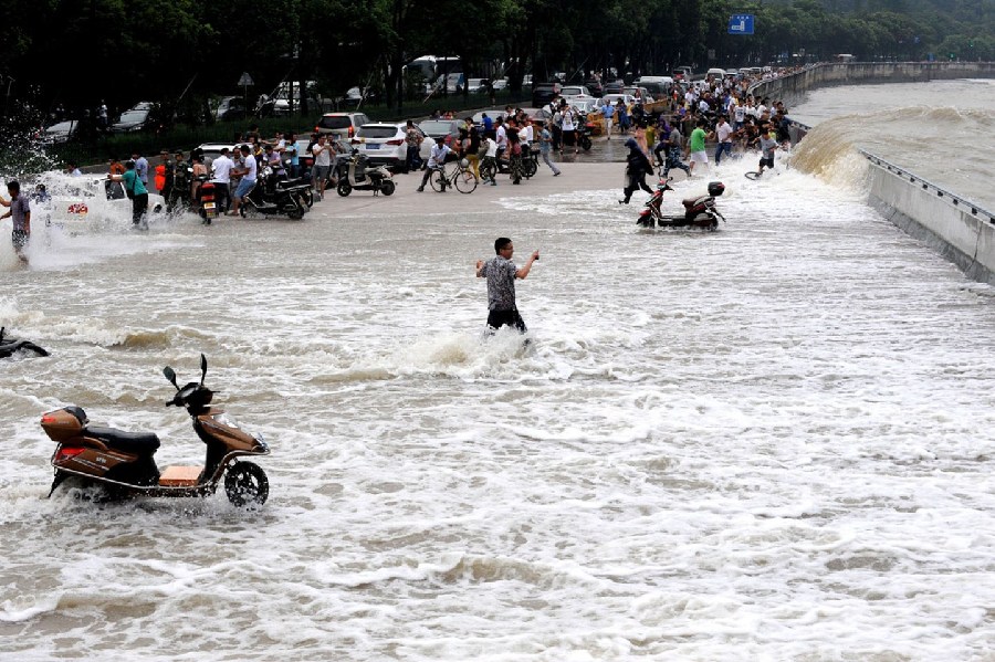 2014年8月15日，杭州，錢江潮水在杭州九溪江堤掀起巨浪，瞬間打濕了觀潮者，一位淡定哥手持手機在潮水中拍攝。