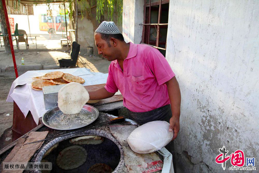 庫爾班從十三歲就開始烤馕，已經烤馕二十多年。為了自己心中的夢想一家人從喀什葉城縣來到哈密。中國網圖片庫 孫繼虎/攝