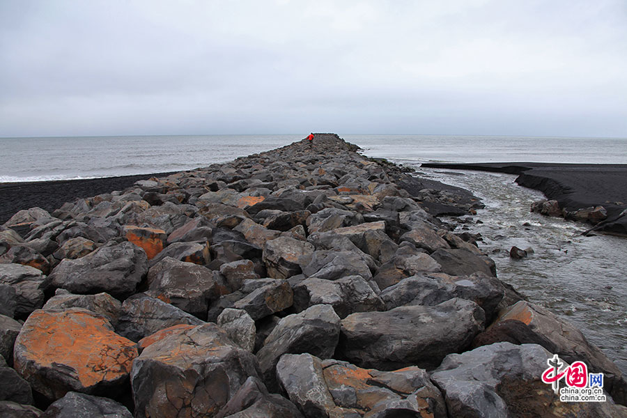 黑沙滩上有一条石头堆起的长堤