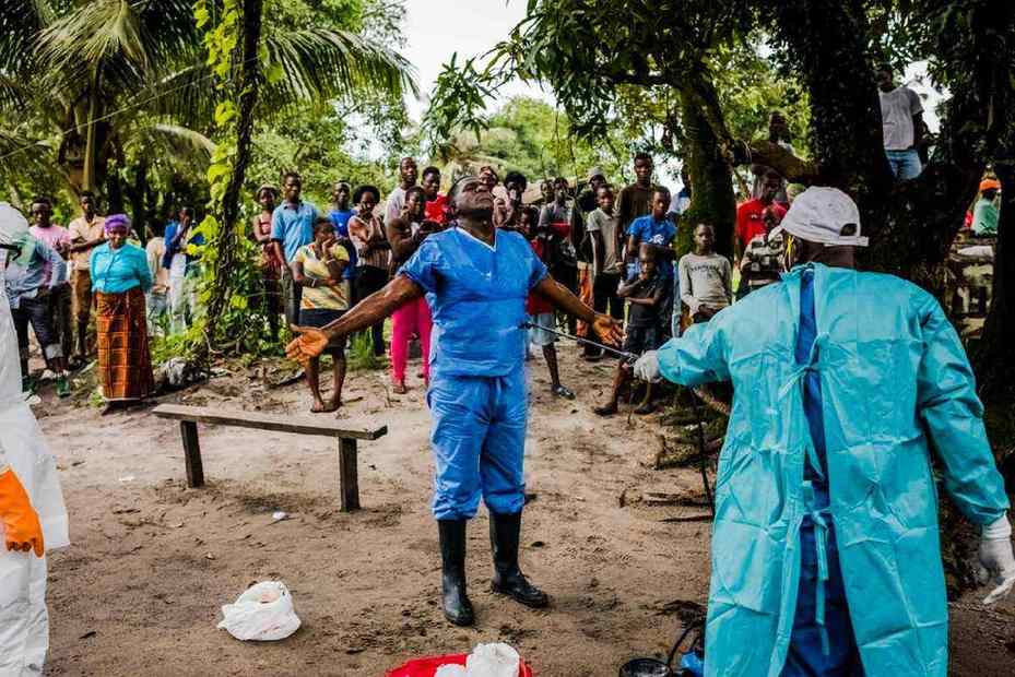 2014年9月6日，在賴比瑞亞首都蒙羅維亞，一名賴比瑞亞紅十字會殯儀小組的成員在移走了一名埃博拉疑似患者的遺體之後，同事正在為他消毒。