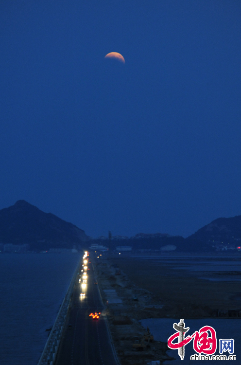 2014年10月8日晚在江蘇連雲港市海濱上空拍攝的“帶食”而出的月亮。 中國網圖片庫 耿玉和攝影