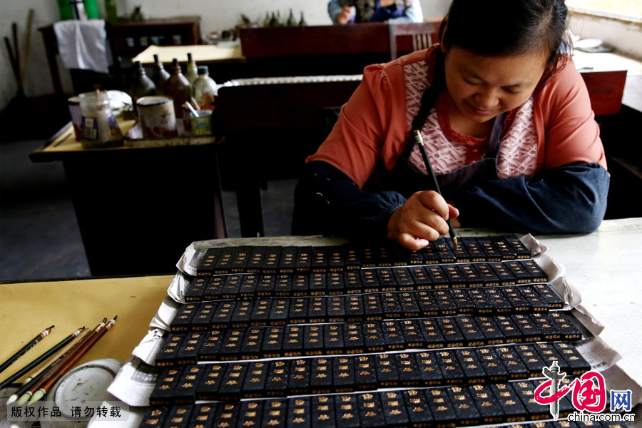 工人正在安徽省黄山市文墨厂里为徽墨描金。
