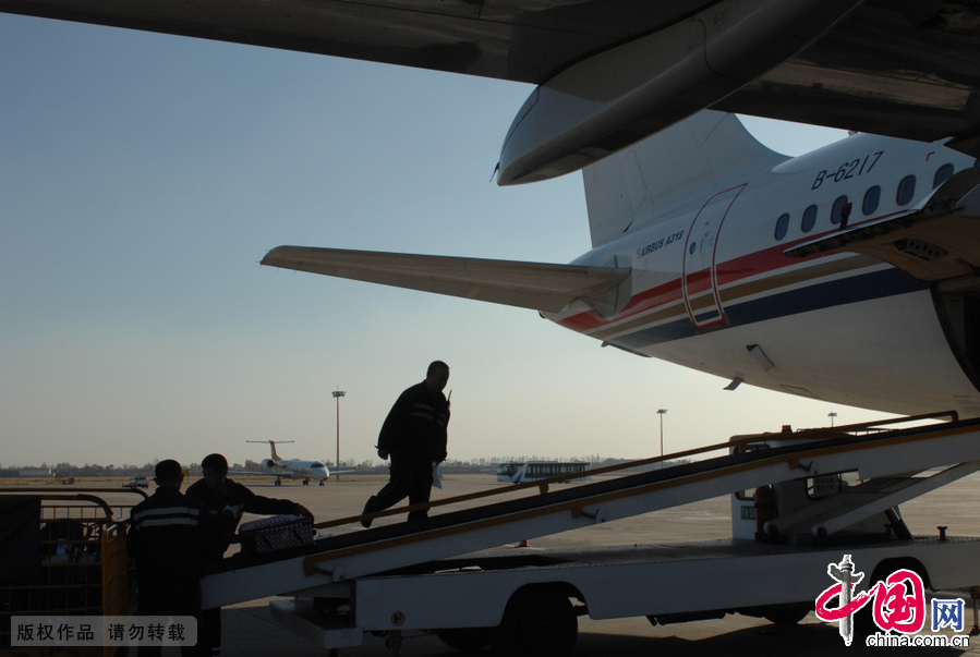 2014年11月04日，內蒙古自治區呼和浩特白塔國際機場，一架飛機降落後工作人員進行行李分揀。