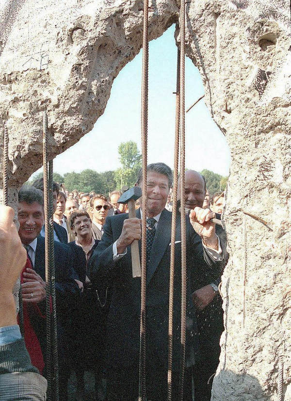 1990年9月12日，美国前总统李根访德期间前往柏林墙旧址，图片上的里根正在用锤子凿柏林墙。