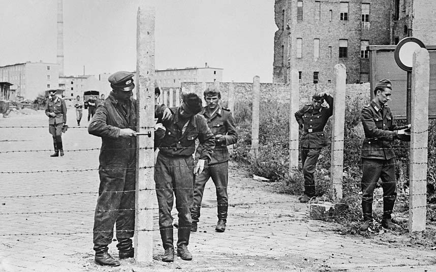 1961年8月14日，东德人民军士兵正在为建柏林墙而架设铁丝网栅栏。
