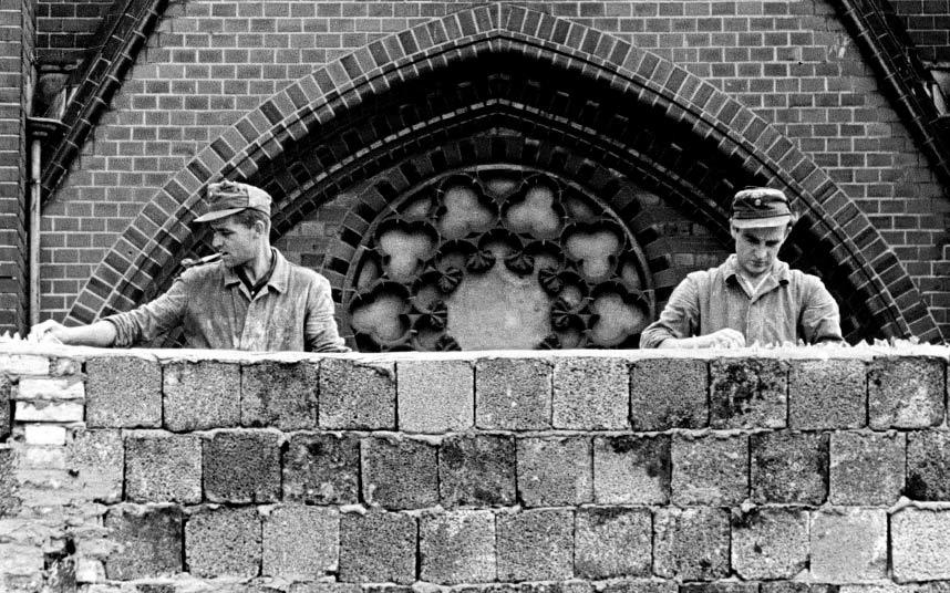 1961年8月22日，为防止东德人逃往西德，两名东德工人在15英尺（4.6米）的柏林墙上放玻璃渣。 