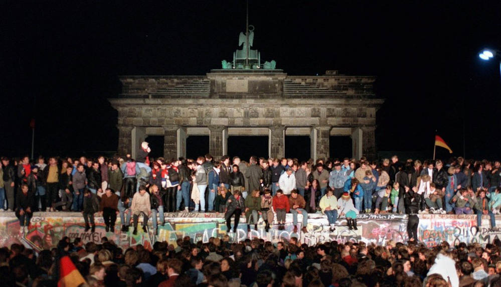 1989年11月10日，德国人站在柏林墙上庆祝东、西德边境开放。 