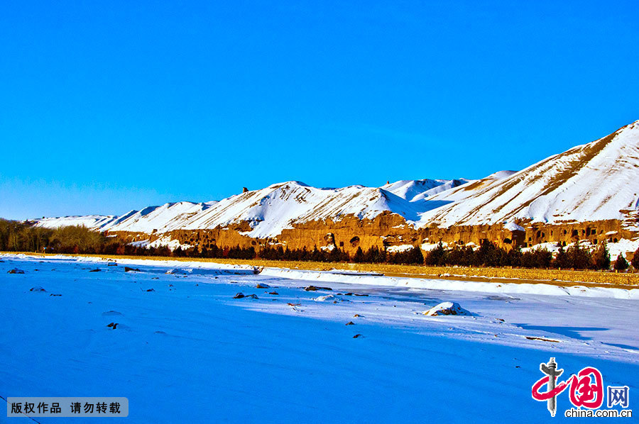 图为雪后的敦煌，摄于莫高窟北区。在2012年第一场雪后的清晨，崖体的颜色和雪的颜色相映成趣，十分美丽。 中国网图片库 徐海洋 摄