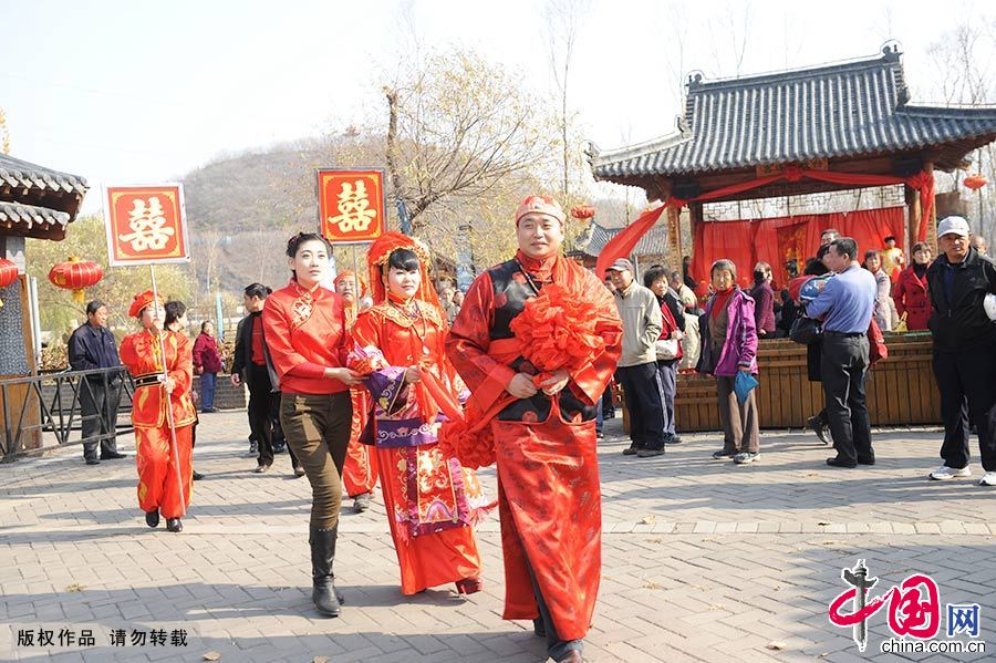 新郎手拿大红绸子牵引新娘前行。中国网图片库 王明铭/摄