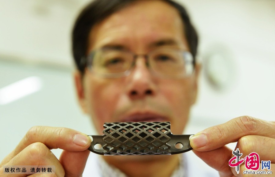 　 2014年12月11日，浙江省杭州市，浙江大学附属第一医院骨科林向进主任在展利用3D激光打印技术制成的钛合金人工椎体。中国网图片库 龙巍 摄影