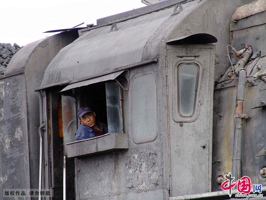  開蒸汽火車，至少需要三個人：一名司機、一名副司機和一名司爐協同合作。作為司機的眼睛，副駕駛位置非常重要，一年四季不論寒暑風雨，都要將頭探出窗外，目不轉睛地盯著前方，為司機來“導航”。蒸汽機車的司機室準確的講在第二節車廂，第一節裏裝著巨大的蒸汽機車，“導航”馬師傅從這間窗戶裏看著指揮。中國網圖片庫 孫繼虎/攝