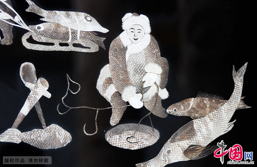  鱼皮画是赫哲族传统的艺术品种。通过对鱼皮的粘贴和镂刻，以独特的形式，从不同角度表现了赫哲族人民的聪明才智和审美的群体意识。图为描绘冬钓的鱼皮画。中国网图片库 韩加君/摄